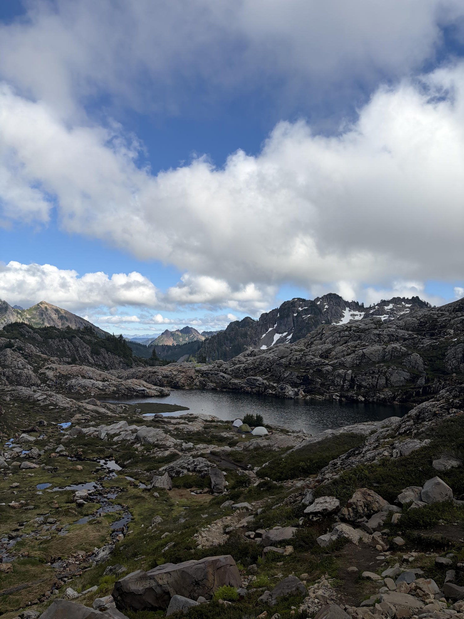 Alpine lake ringed by granite slabs and jagged peaks under a bright sky in Gothic Basin