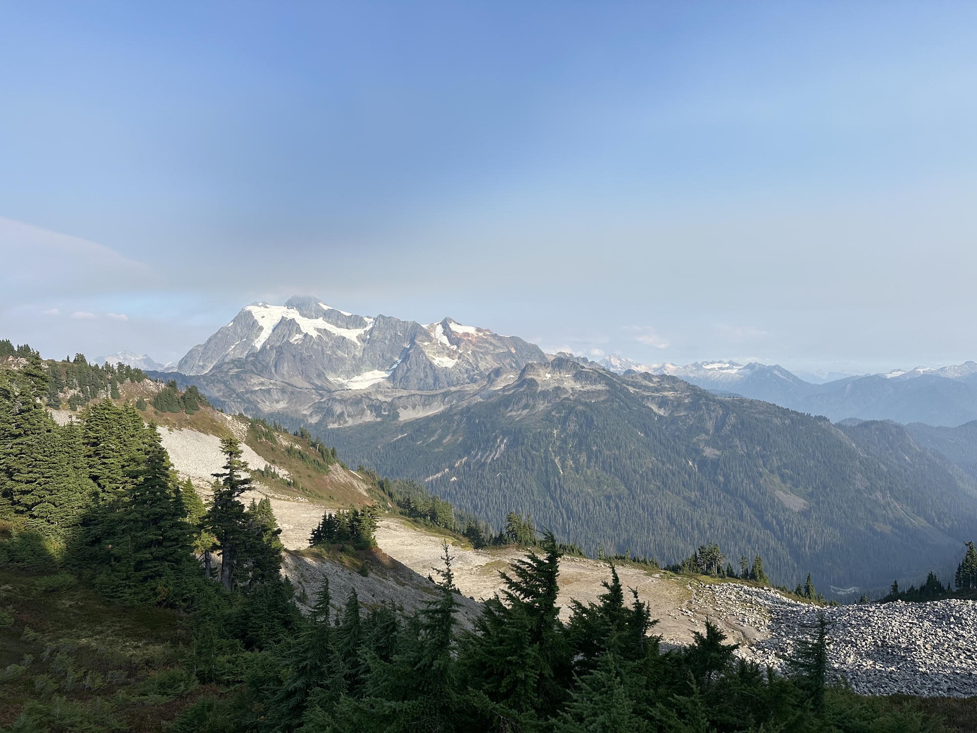 The glaciated summit of Mount Shuksan rising beyond forested ridgelines from Ptarmigan Ridge